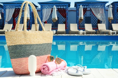 Beach accessories on wooden deck near swimming pool. Space for text