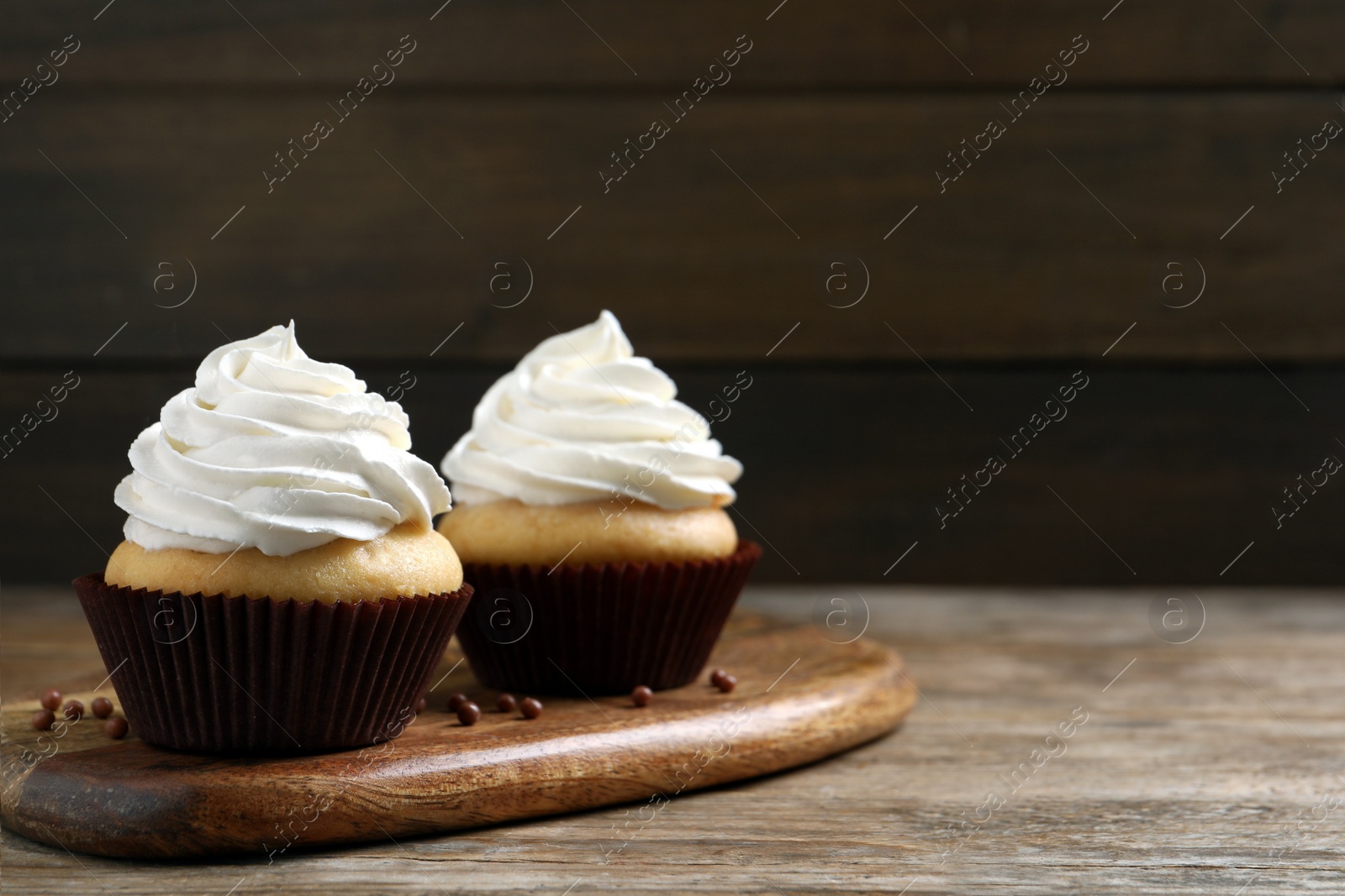 Photo of Delicious cupcakes with cream on wooden table. Space for text