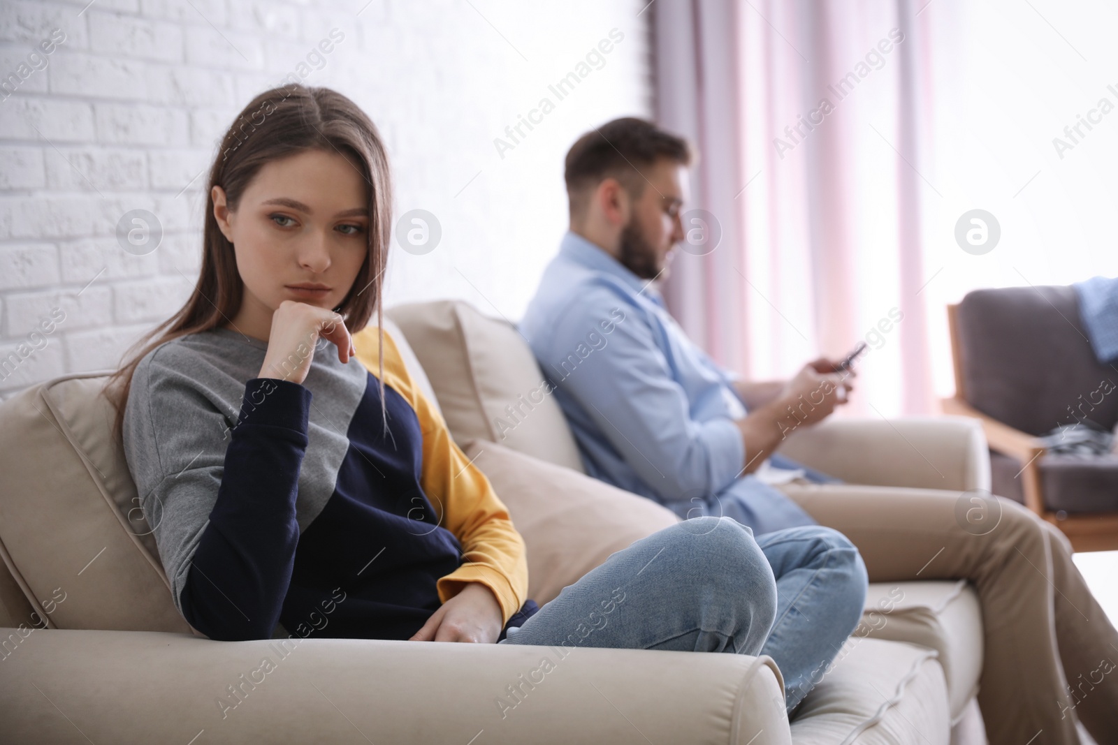 Photo of Young man preferring smartphone over his girlfriend at home. Relationship problems