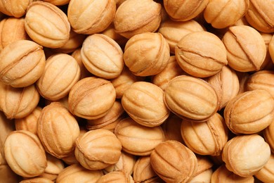 Delicious nut shaped cookies with boiled condensed milk as background, top view