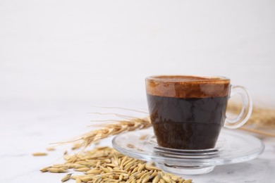 Photo of Cup of barley coffee, grains and spike on light table, closeup. Space for text