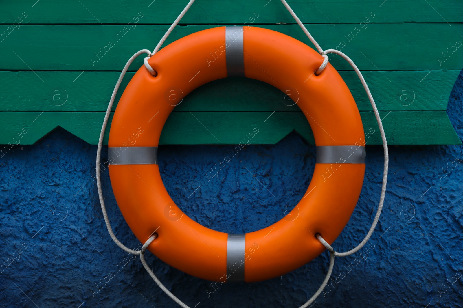 Photo of Orange lifebuoy hanging on wall. Rescue equipment