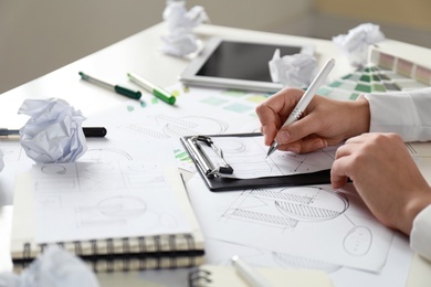 Female designer working at wooden table, closeup