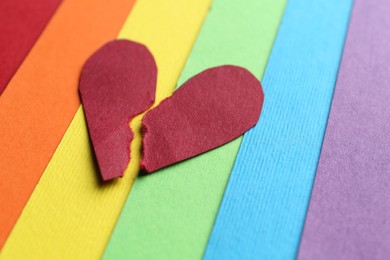 Halves of torn paper heart on colorful background. Breakup concept