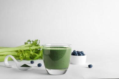 Composition with glass of spirulina smoothie on white background. Space for text