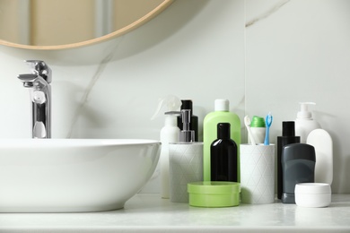 Photo of Stick deodorant and different toiletry on countertop in bathroom