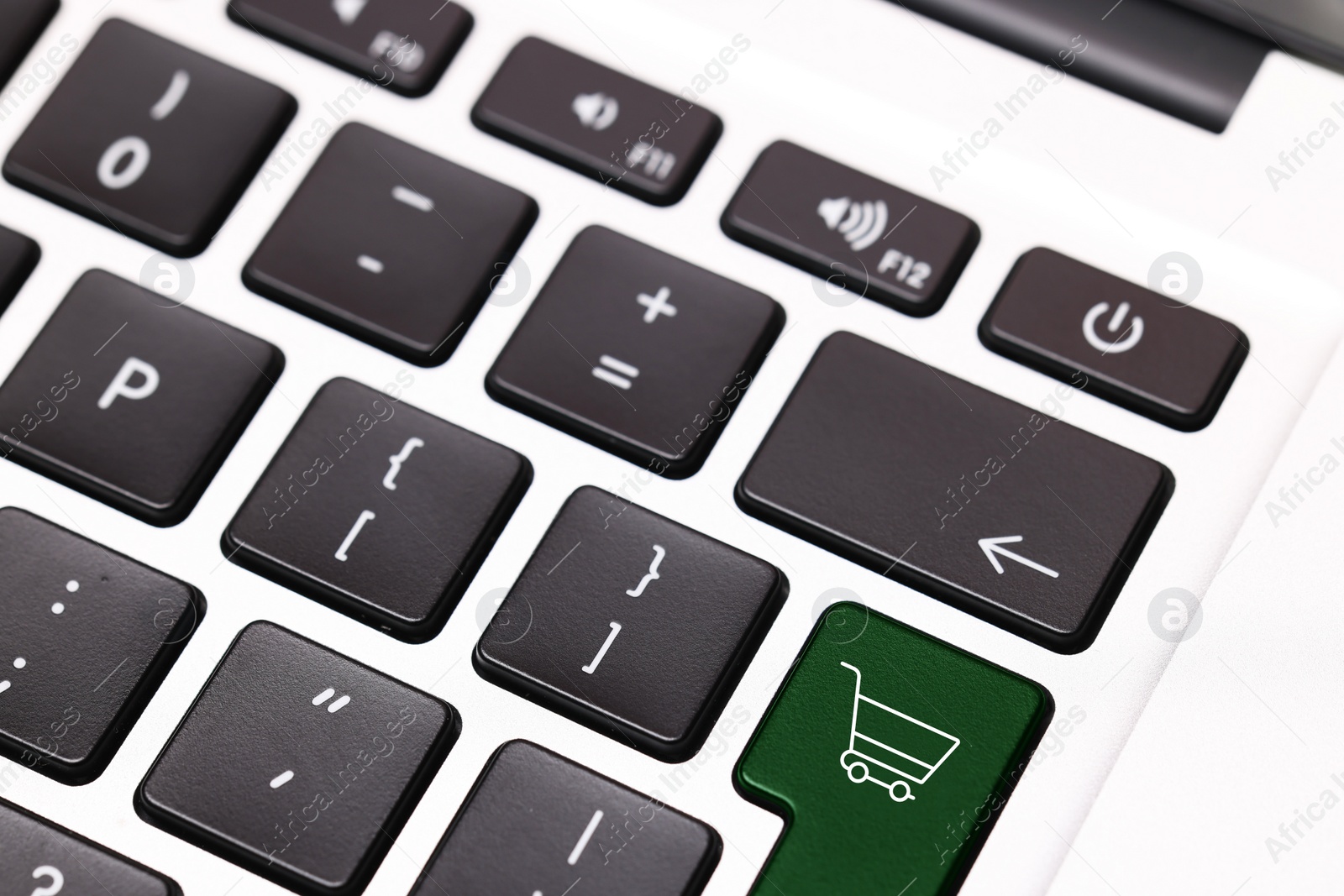 Image of Internet store. Green button with shopping cart on computer keyboard, closeup