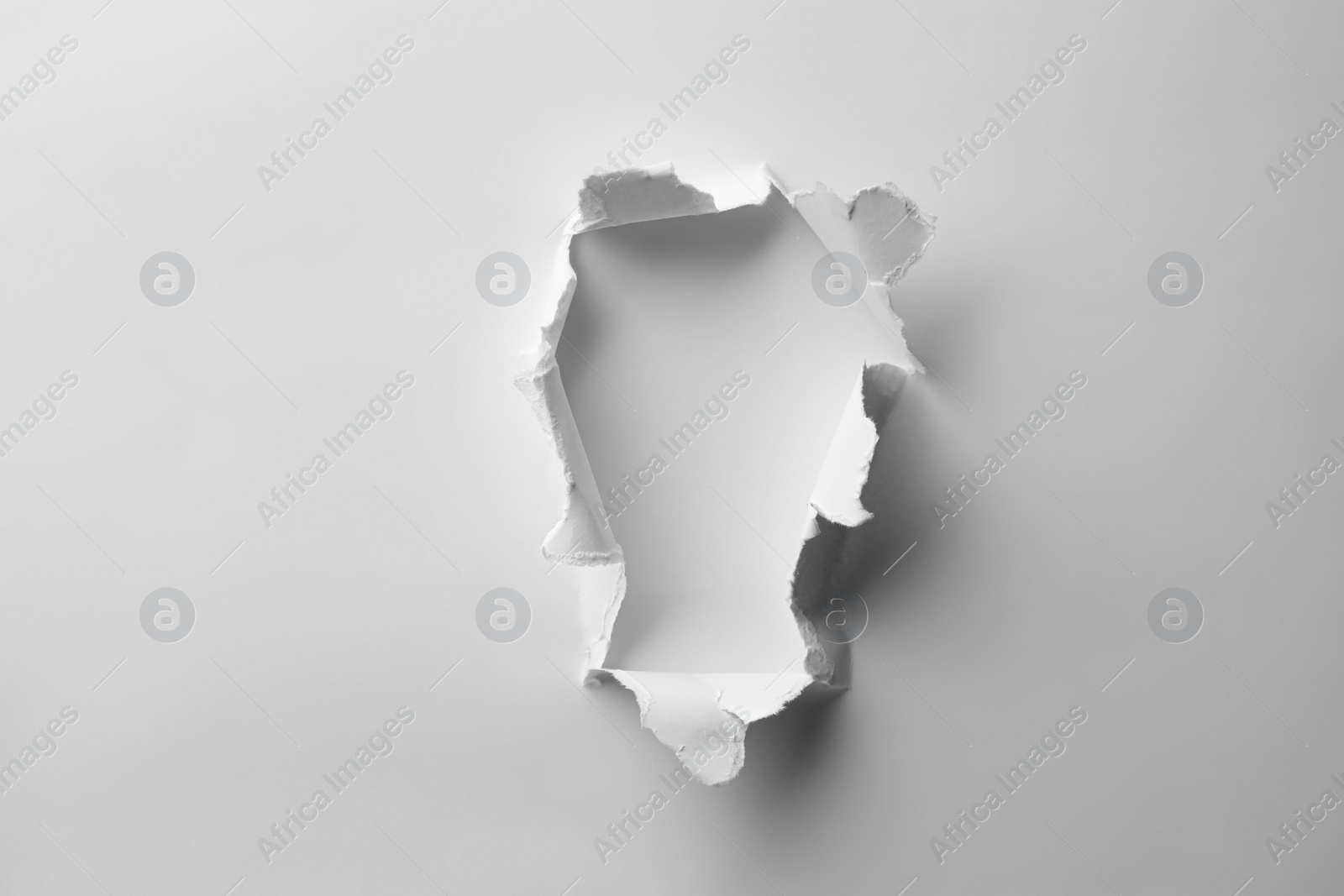 Photo of Hole in white paper on light background