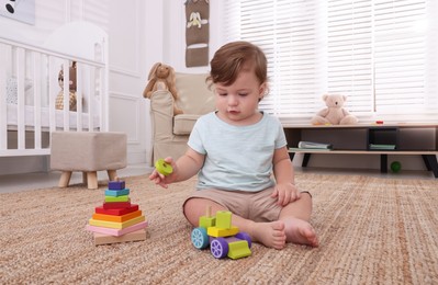 Photo of Cute little boy playing with toys on floor indoors