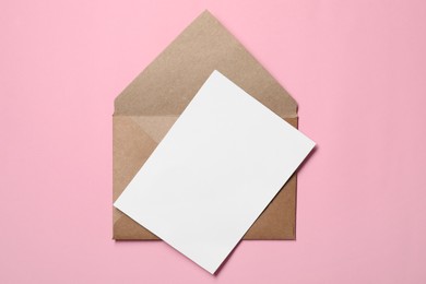 Photo of Letter envelope and card on pink background, top view