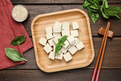 Delicious tofu with basil served on wooden table, flat lay