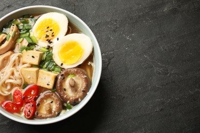 Photo of Noodle soup. Bowl of delicious ramen on black table, top view. Space for text