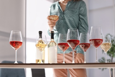 Photo of Glasses and bottles of wine and blurred woman on background