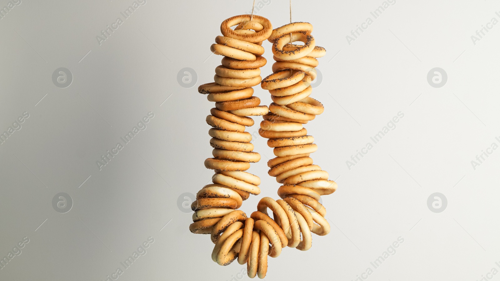Photo of Bunch of delicious ring shaped Sushki (dry bagels) hanging on light grey background