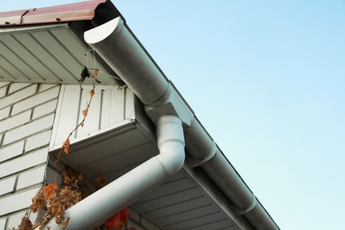 Rain gutter system with drainpipe on house outdoors, low angle view