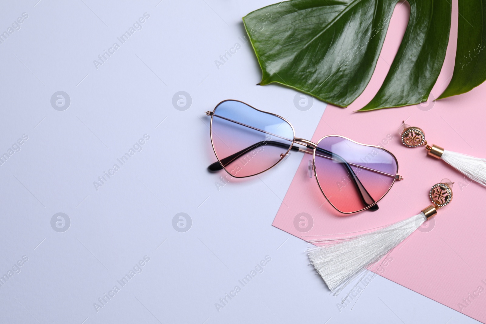 Photo of Stylish elegant heart shaped sunglasses on light background, top view. Space for text