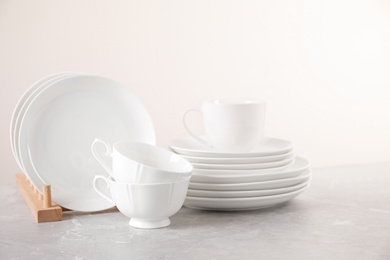 Photo of Set of clean tableware on light grey marble table