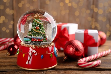 Photo of Beautiful Christmas snow globe and festive decor on wooden table