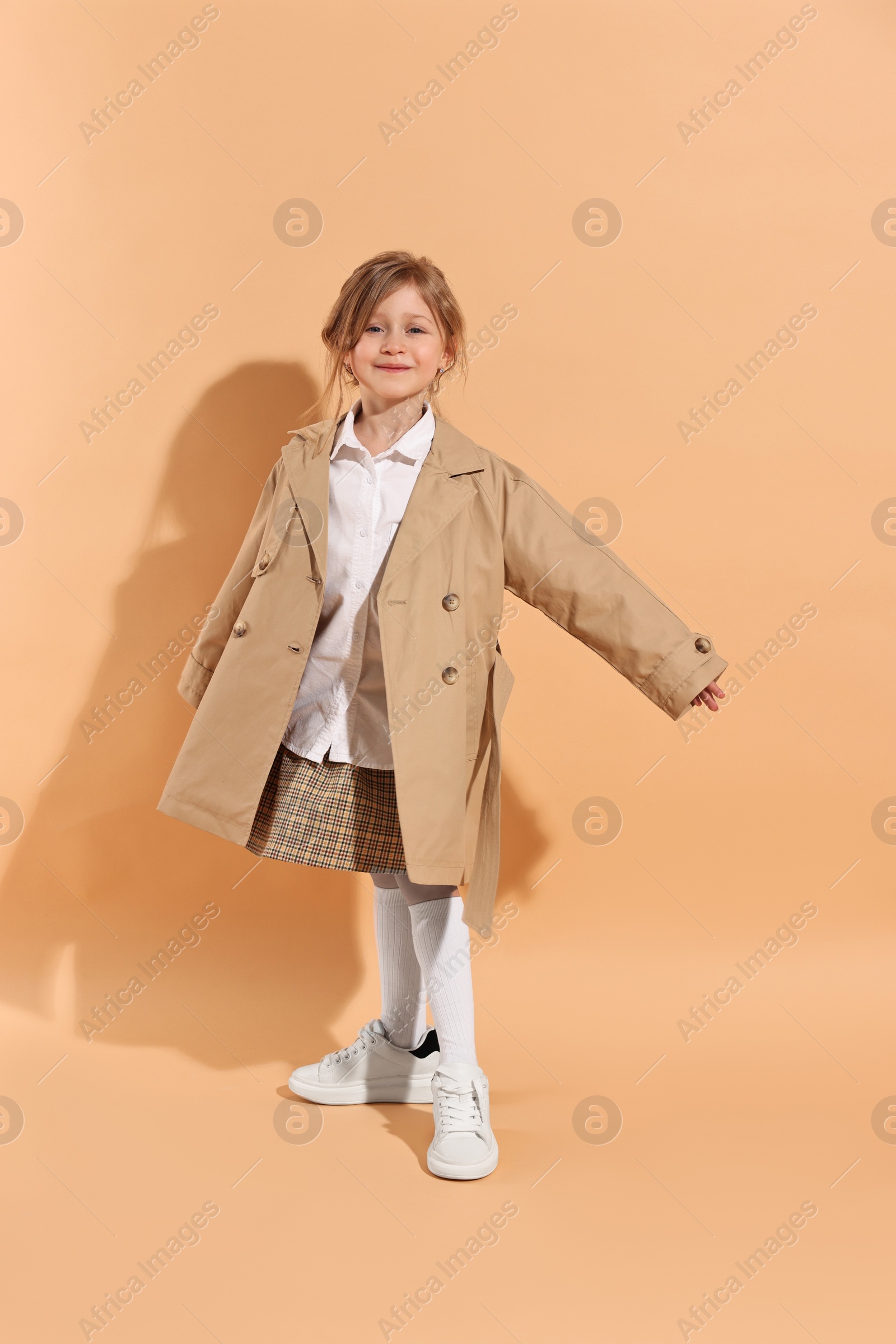 Photo of Fashion concept. Stylish girl posing on pale orange background