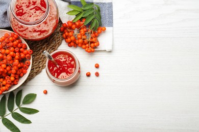 Flat lay composition with delicious rowan jam on white wooden table. Space for text