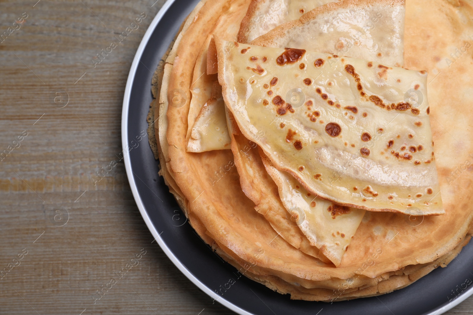 Photo of Stack of delicious crepes on grey wooden table, top view