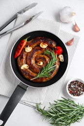 Delicious homemade sausage with garlic, tomato, rosemary and chili served on white table, flat lay