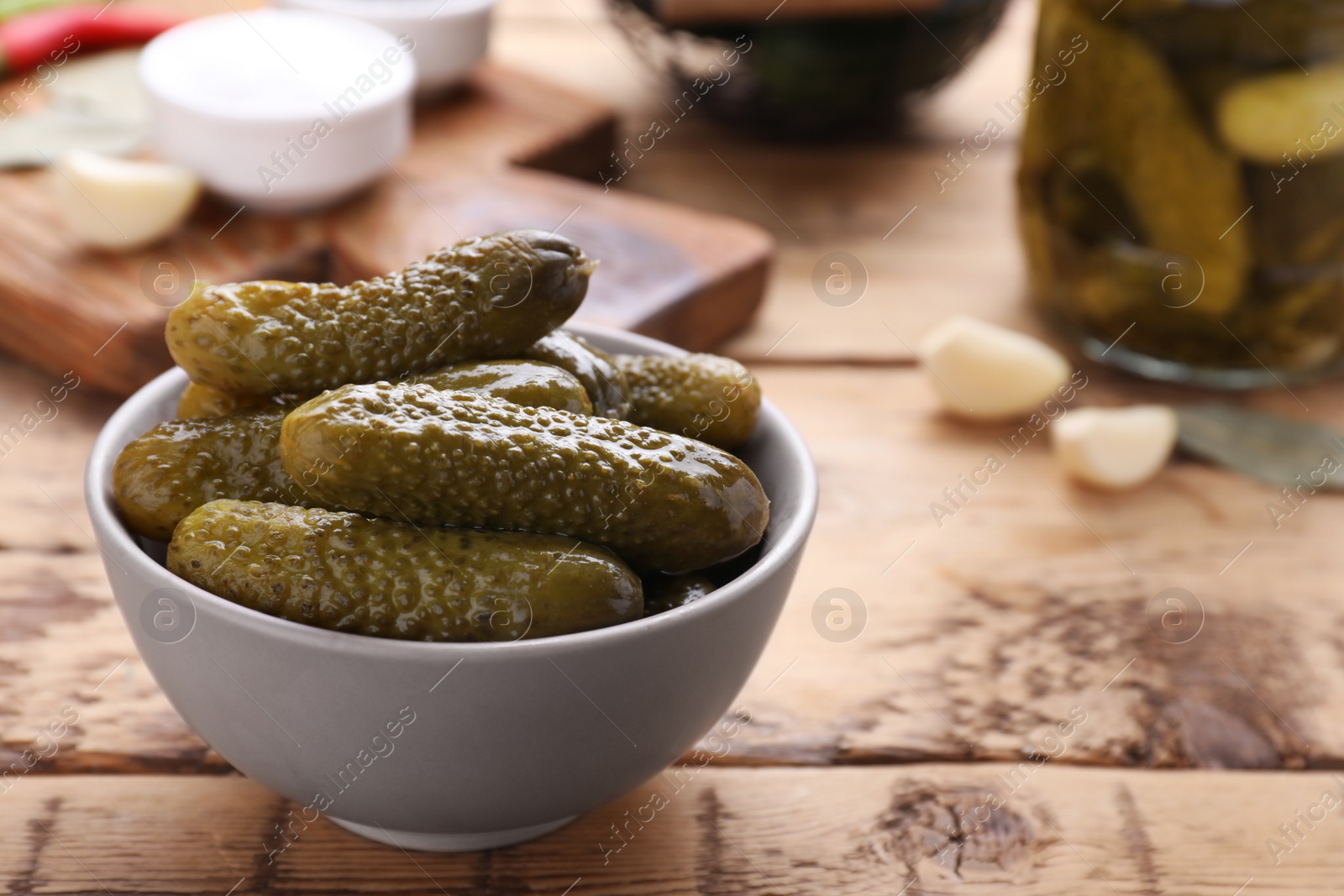 Photo of Bowl of pickled cucumbers and ingredients on wooden table