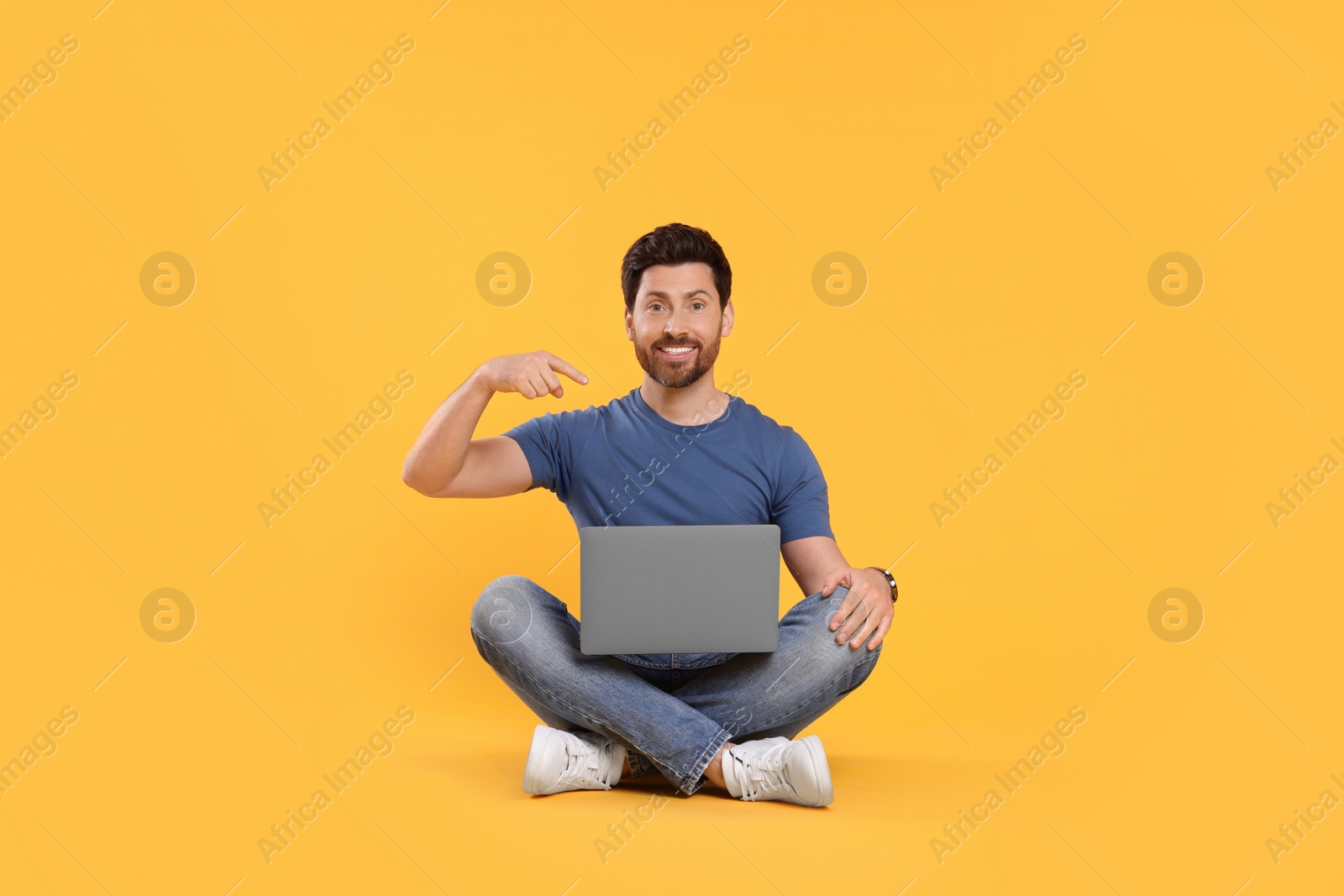 Photo of Happy man with laptop on yellow background