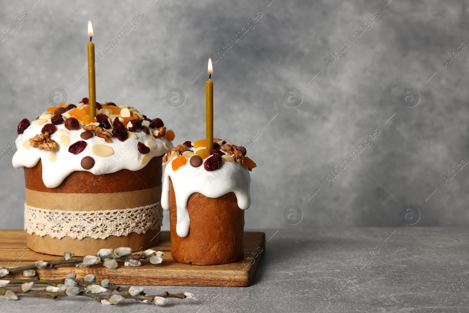 Photo of Tasty Easter cakes and willow branches on grey table. Space for text