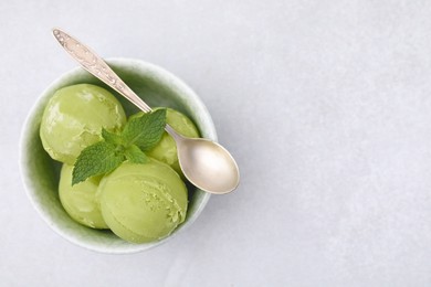 Tasty matcha ice cream and spoon in bowl on light grey table, top view. Space for text