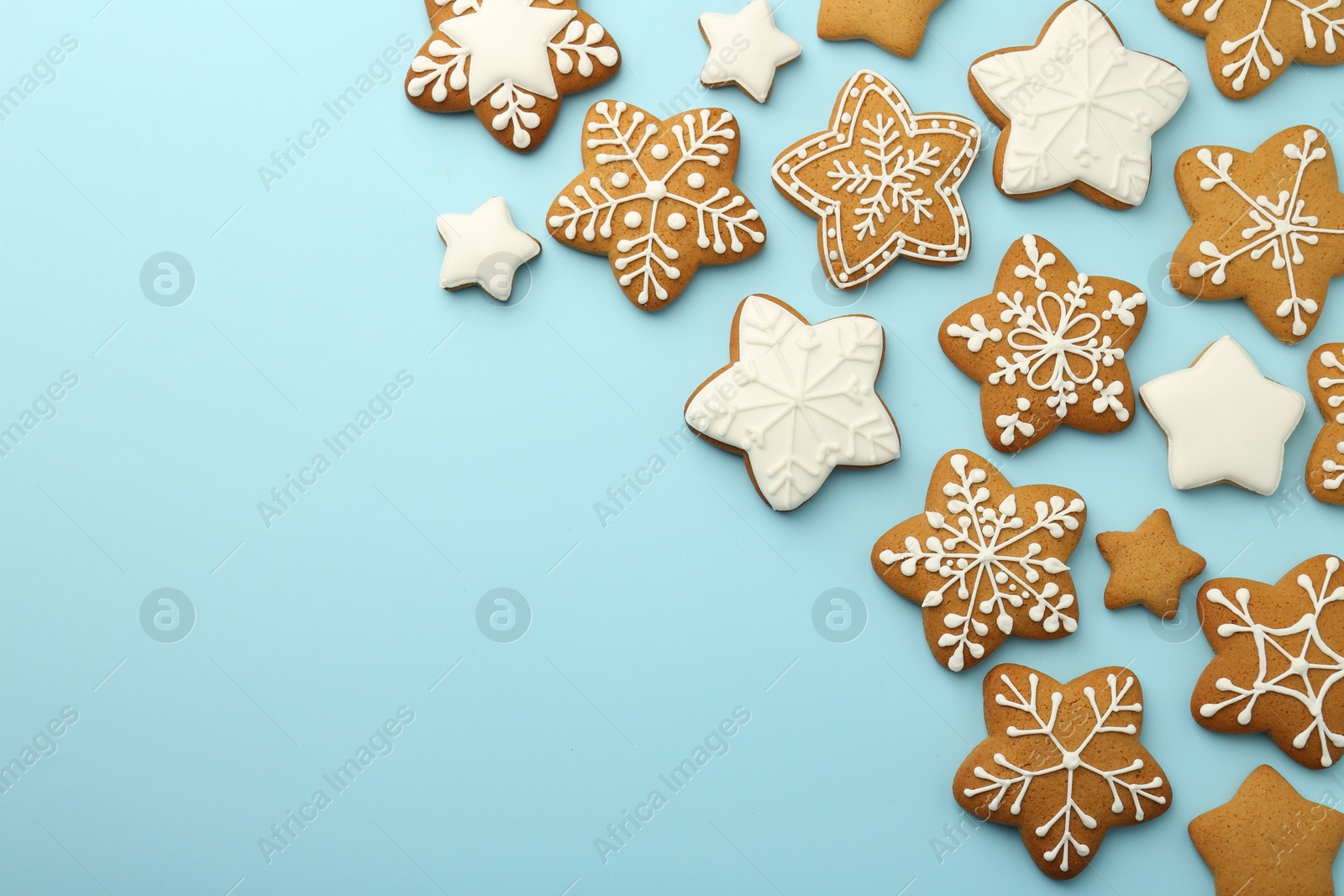 Photo of Tasty star shaped Christmas cookies with icing on light blue background, flat lay. Space for text