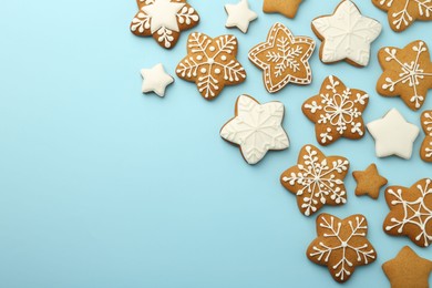 Photo of Tasty star shaped Christmas cookies with icing on light blue background, flat lay. Space for text