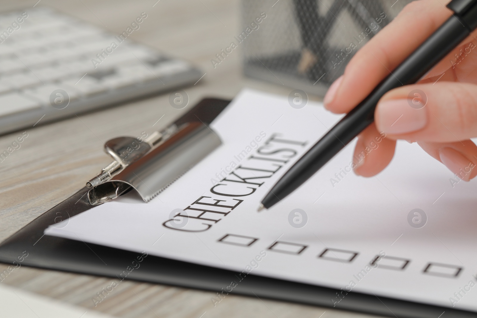 Photo of Woman filling Checklist at wooden table, closeup