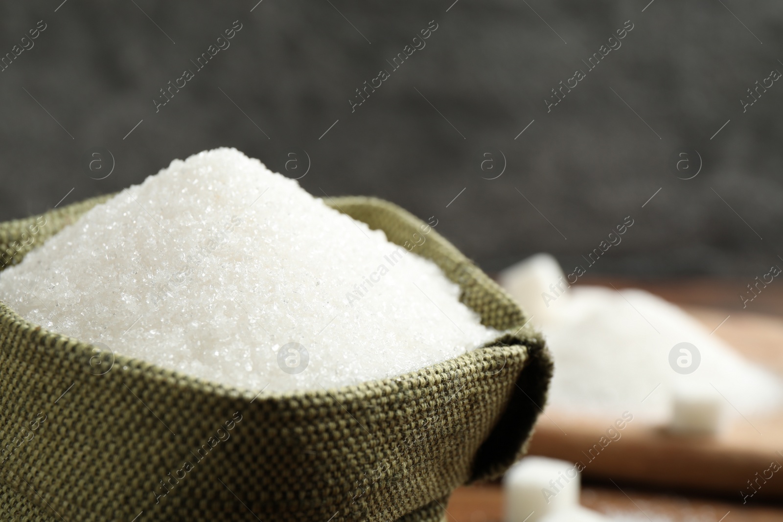 Photo of Granulated sugar in sack on table, closeup