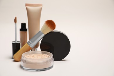 Photo of Loose face powder and other makeup products on light background, space for text