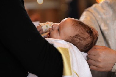 Photo of Man holding adorable baby in church during baptism ceremony, closeup