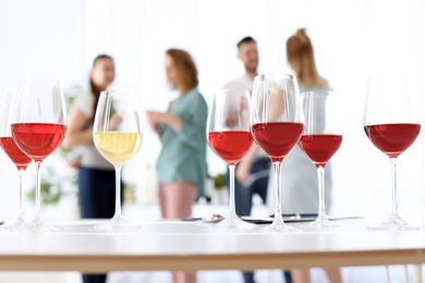 Glasses with delicious wine and blurred people on background