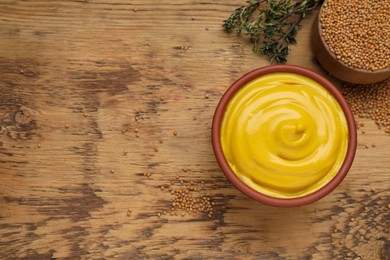 Photo of Delicious mustard, seeds and thyme on wooden table, flat lay. Space for text