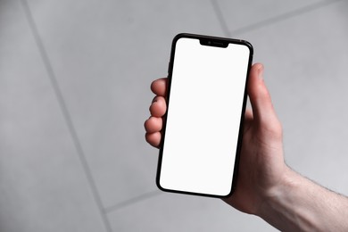 Man holding smartphone with blank screen indoors, top view. Mockup for design