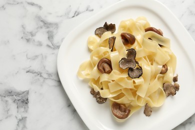 Photo of Tasty tagliatelle with truffle on white marble table, top view