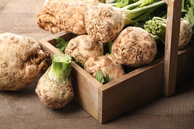 Fresh raw celery roots and crate on wooden table