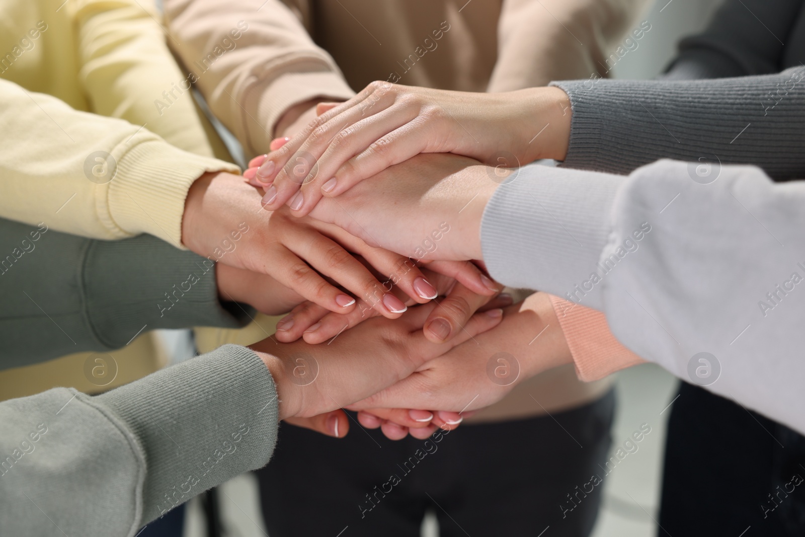 Photo of Group of people holding hands together indoors, closeup. Unity concept