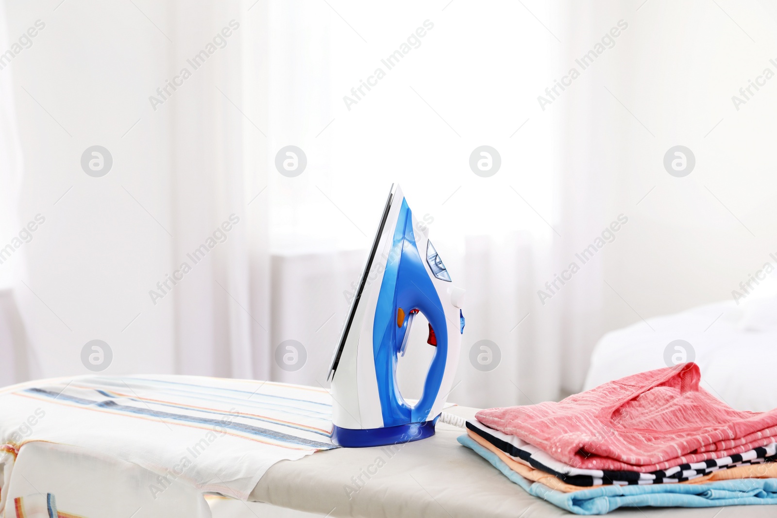 Photo of Modern electric iron on board indoors, space for text. Household appliance