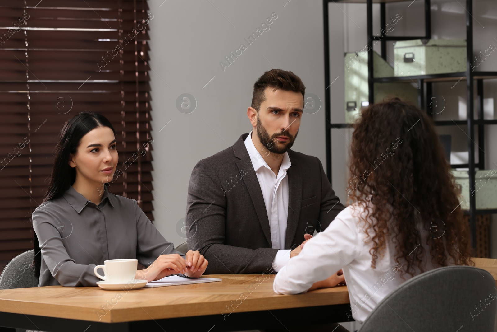 Photo of Coworkers conducting job interview with African American woman in office. Racism concept