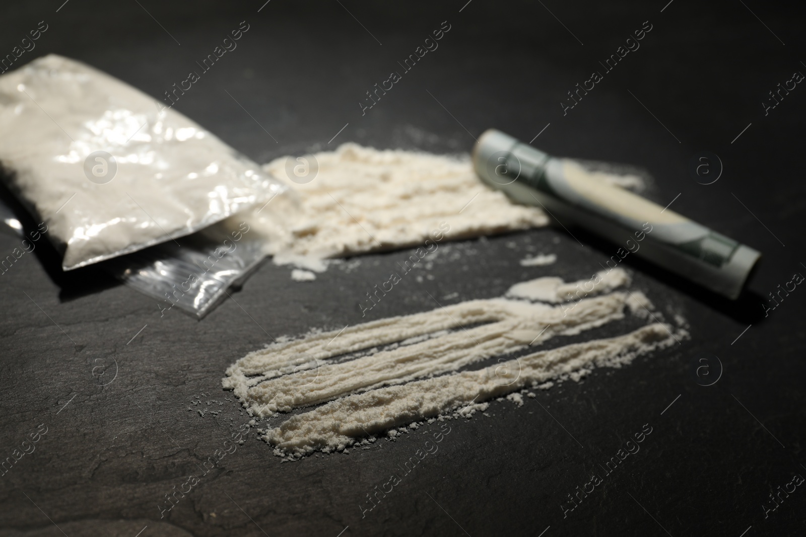 Photo of Drug addiction. Plastic bag with cocaine and rolled dollar banknote on grey textured table, closeup