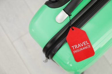 Suitcase with TRAVEL INSURANCE label on floor, top view