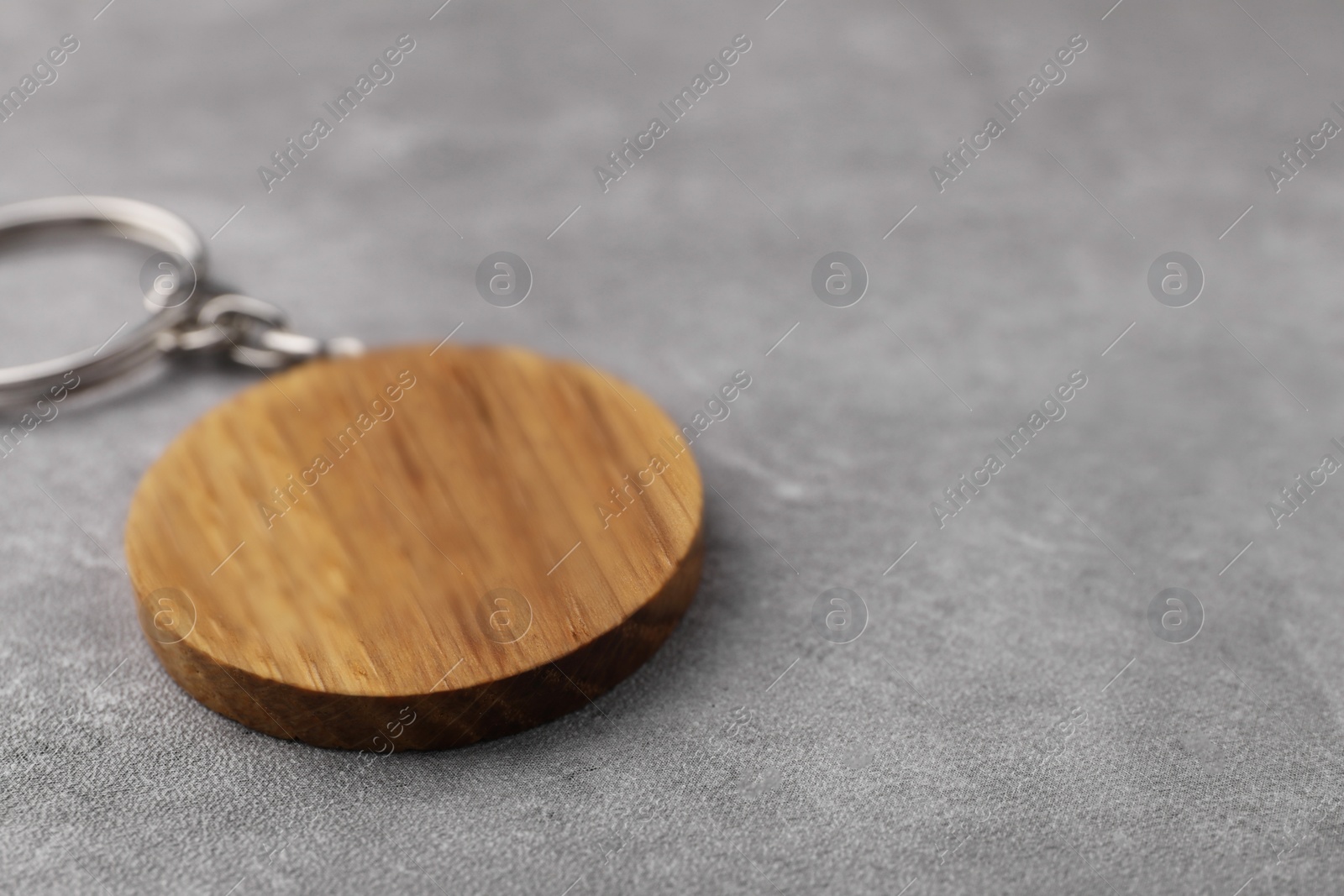 Photo of Wooden keychain in shape of smiley face on grey background, closeup. Space for text