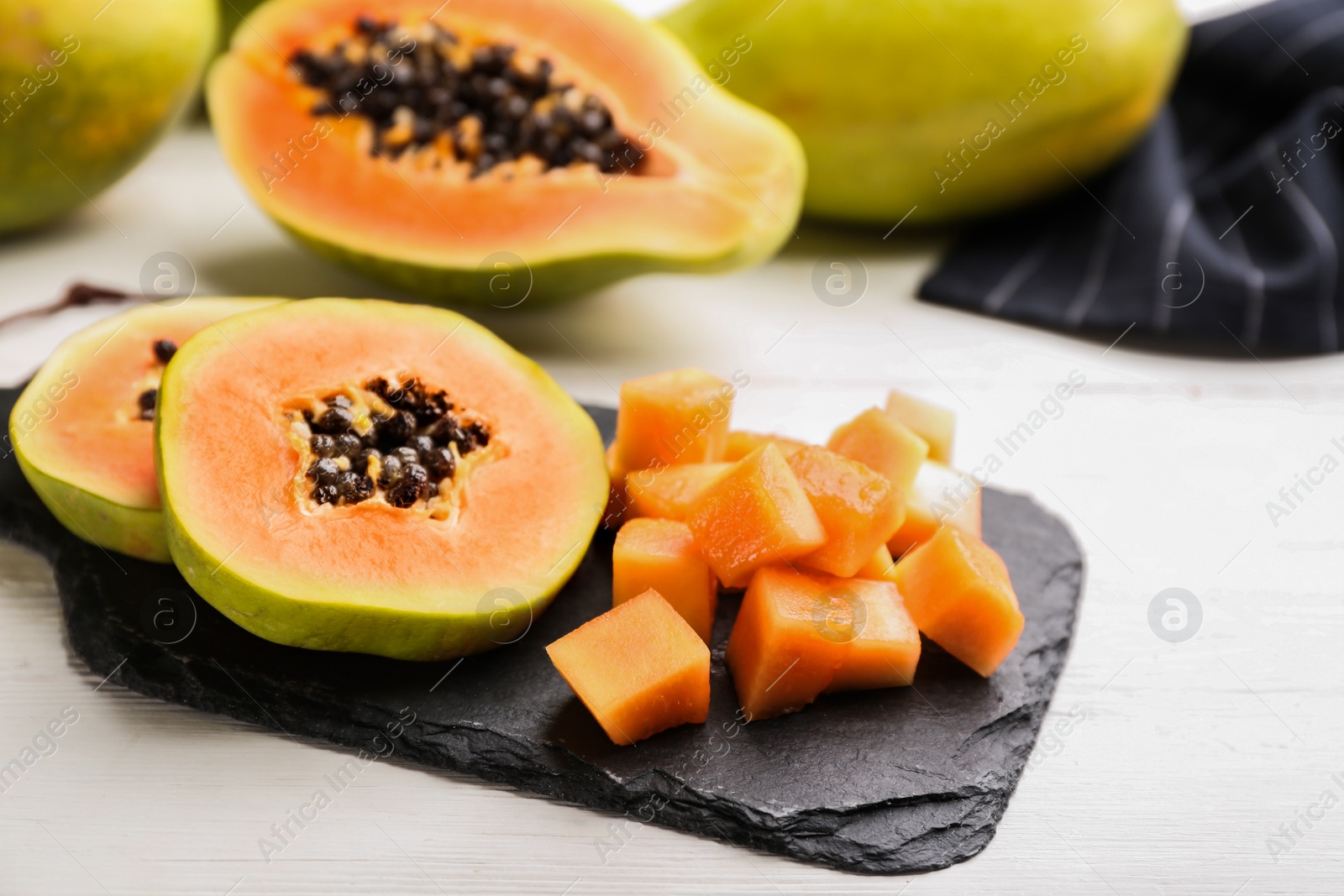 Photo of Fresh cut papaya fruits on white wooden table
