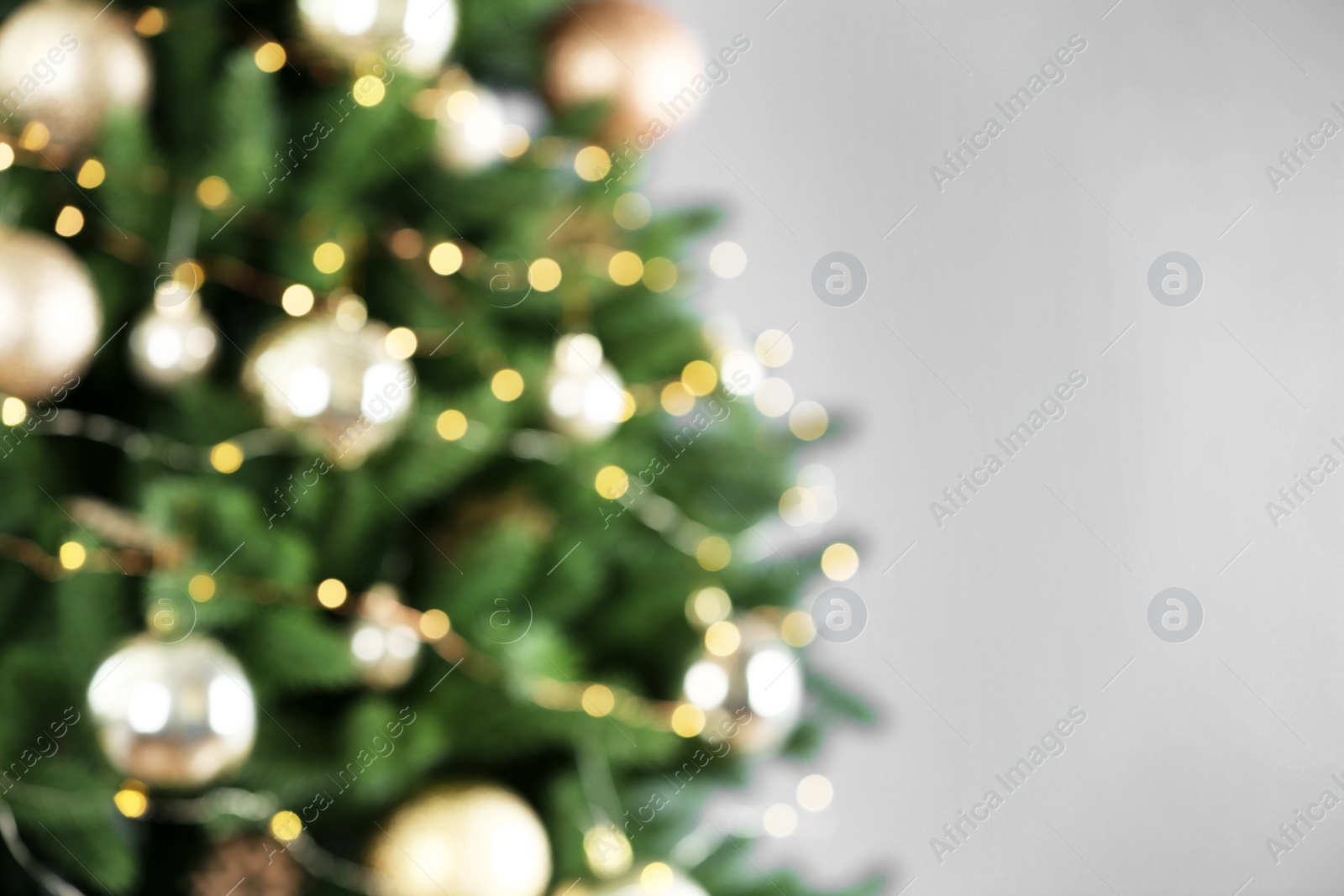 Photo of Beautiful Christmas tree with lights against grey background, blurred view. Space for text