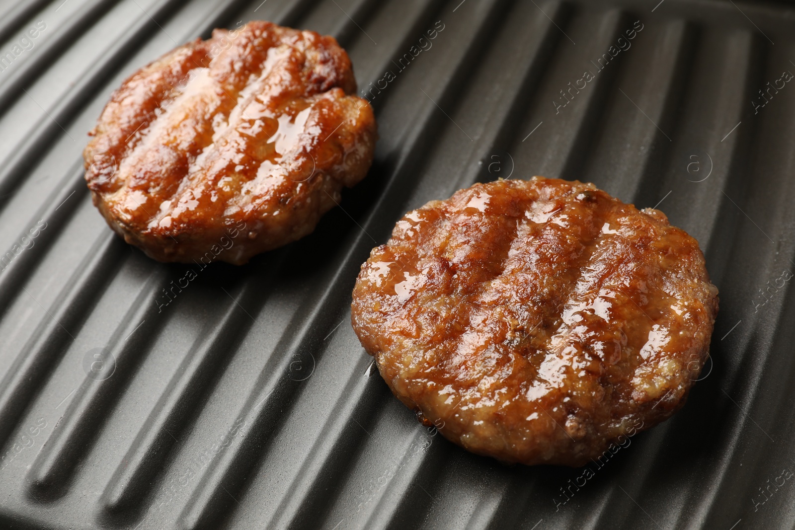 Photo of Delicious hamburger patties on electric grill, closeup